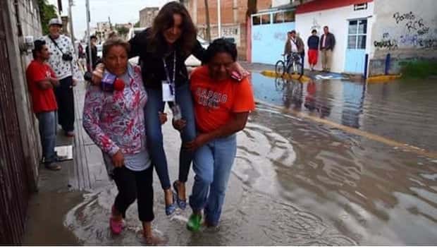 Repórter é carregada por moradoras. (Foto: Divulgação)