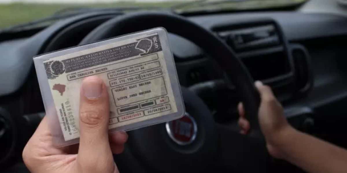 Pessoa segurando CNH dentro de carro (Foto: Reprodução / Internet)