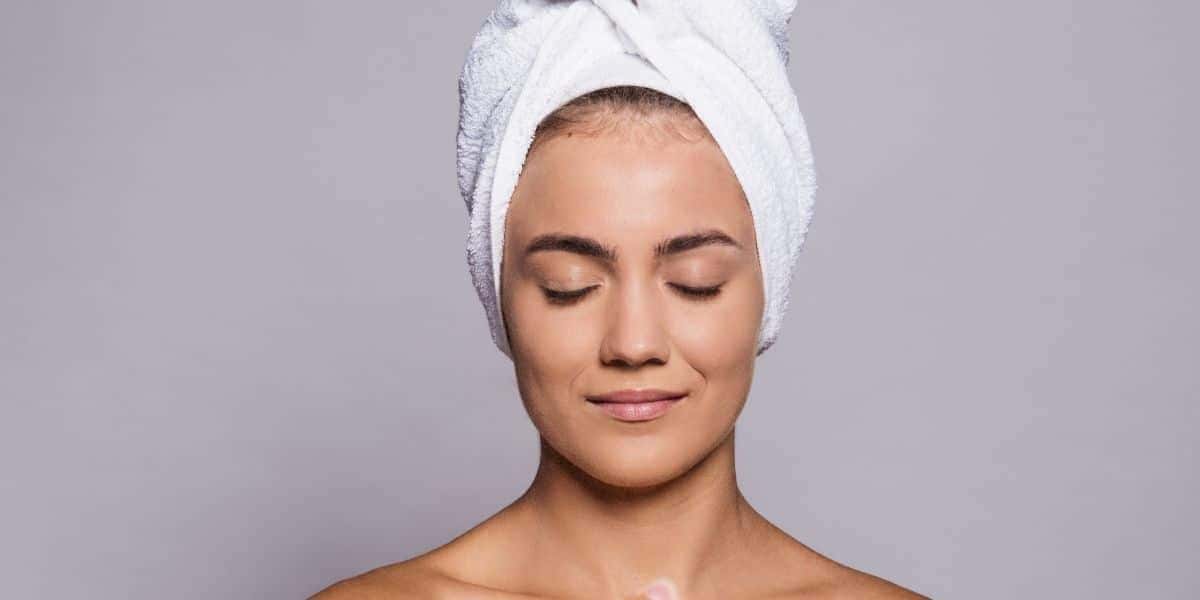 Mulher com toalha na cabeça (Foto: Canva)
