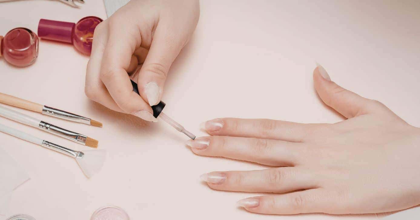 Mulher pintando as unhas (Foto: Canva)