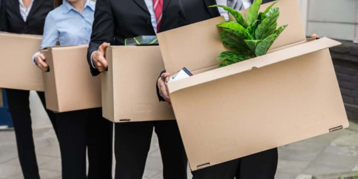 Funcionários demitidos de empresa, com suas coisas pessoais em uma fila - Foto Reprodução Internet
