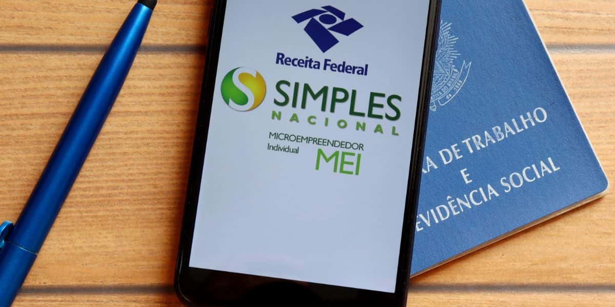 Celular com aplicativo do MEI aberto e Carteira de Trabalho - Foto Reprodução Internet