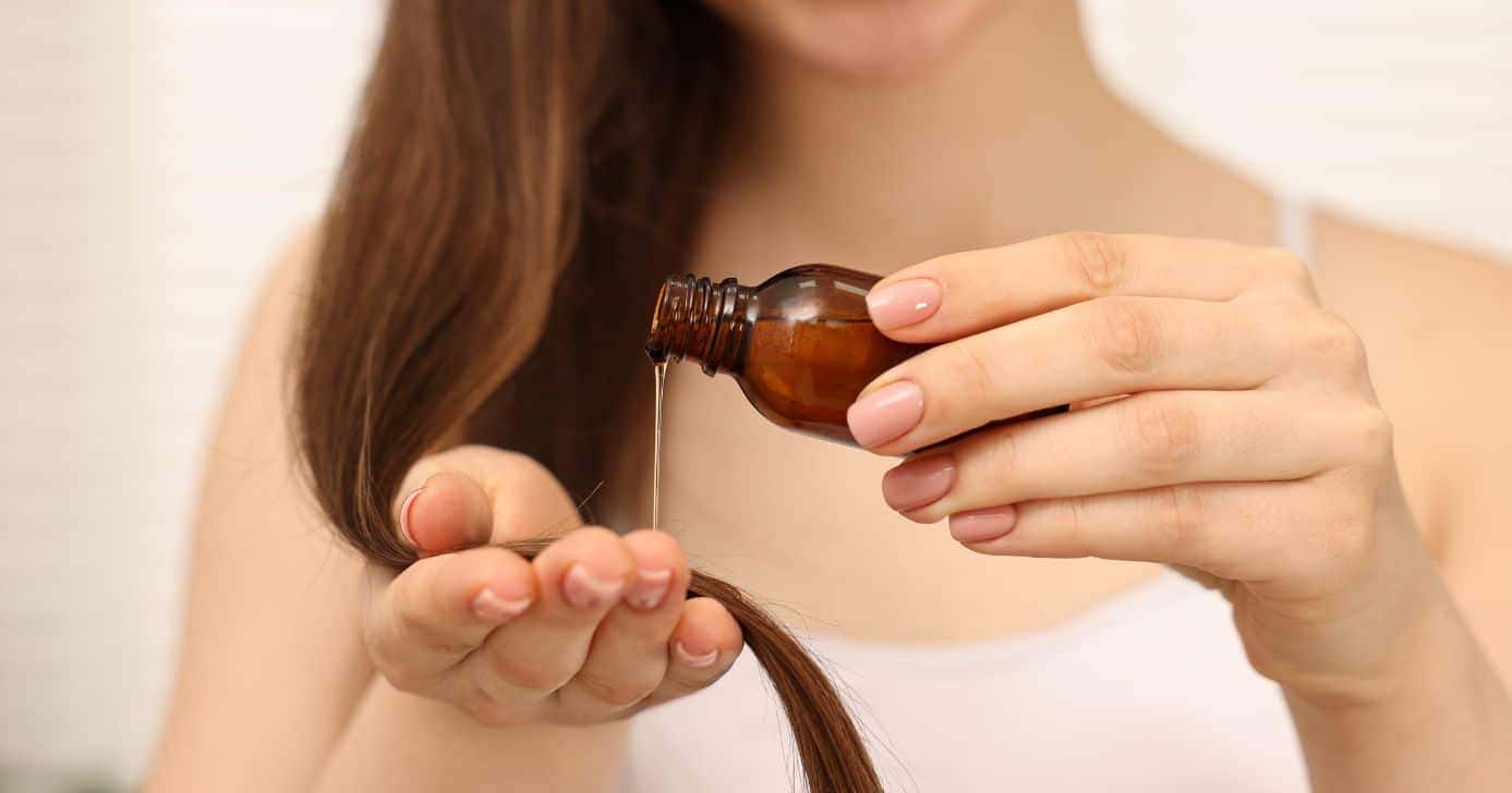 Ilustração de mulher passando óleo no cabelo (Foto: Canva)