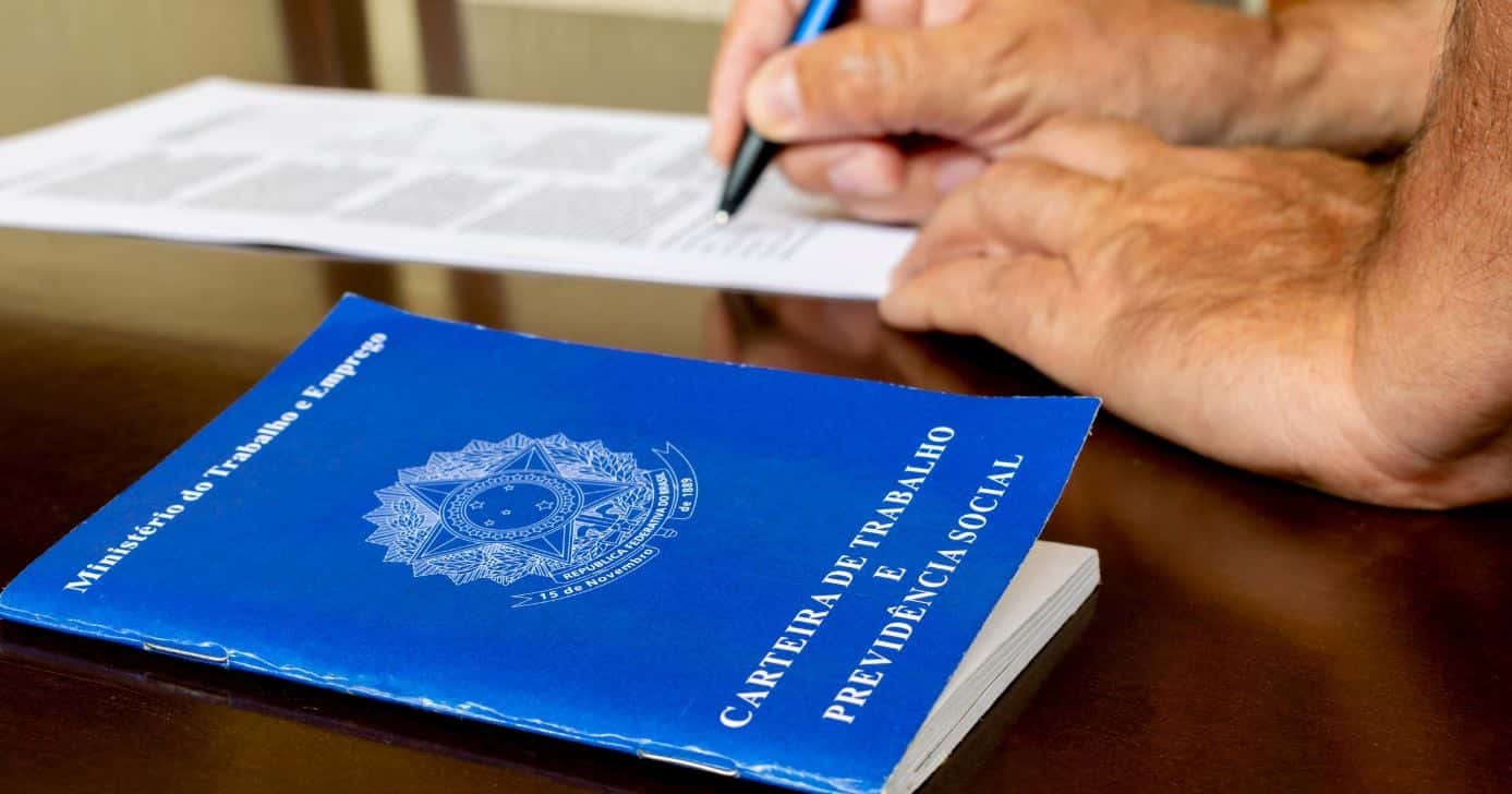 Ilustração homem assinando contrato CLT e carteira de trabalho (Foto: Canva)