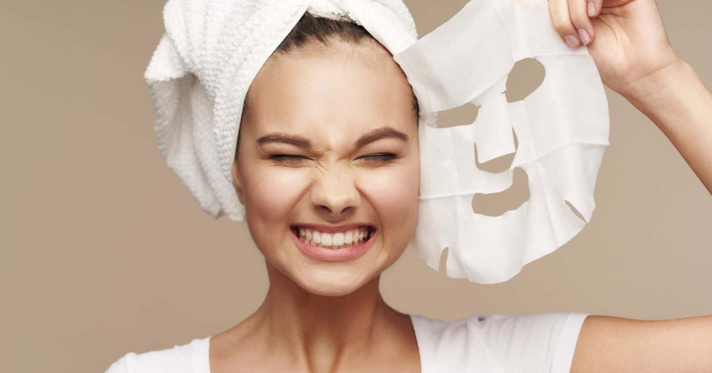 Mulher com máscara facial na mão (Foto: Canva)