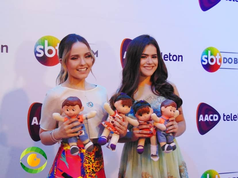 Duas jovens garotas estão sorridentes e seguram bonecos nas mãos Duas jovens garotas estão sorridentes e seguram bonecos nas mãos