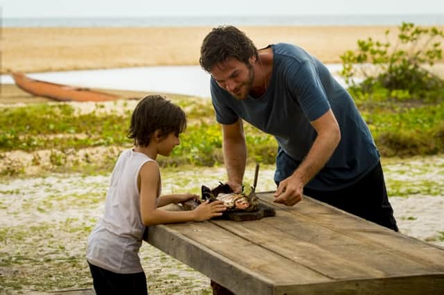Beto (Emilio Dantas) e Ícaro (Thales Miranda) grelham e comem peixe na areia (Foto: Globo/João Cotta)