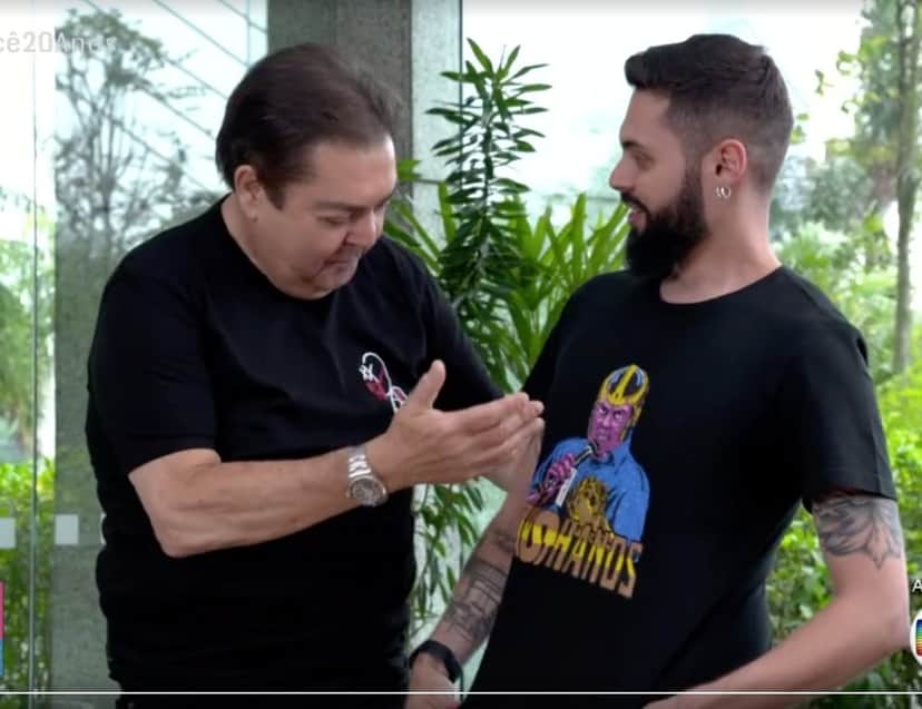 Cauê Fabiano mostrando sua camiseta para Faustão. Foto: Reprodução Cauê Fabiano mostrando sua camiseta para Faustão. Foto: Reprodução