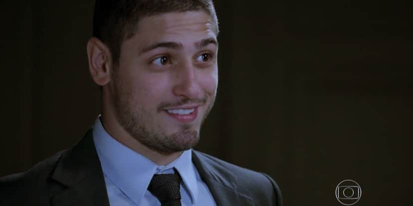 João Lucas em cena da novela Império usando terno cinza, camisa social azul e gravata preta João Lucas em cena da novela Império usando terno cinza, camisa social azul e gravata preta
