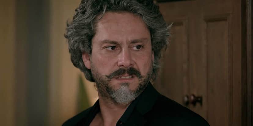 José Alfredo usando camisa preta na frente de porta de madeira em cena da novela Império José Alfredo usando camisa preta na frente de porta de madeira em cena da novela Império