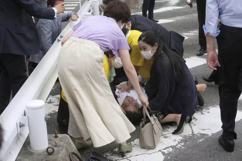 Abe com camisa ensanguentada e mãos no peito caído no chão (Foto: Kyodo / via REUTERS) Abe com camisa ensanguentada e mãos no peito caído no chão (Foto: Kyodo / via REUTERS)