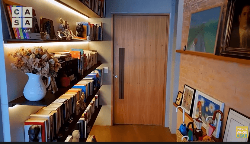 A entrada da casa da atriz Maria Clara Gueiros conta com muitos livros e quadros, apesar de ter muitas coisas, é tudo muito bem organizado (Foto Reprodução/Youtube) A entrada da casa da atriz Maria Clara Gueiros conta com muitos livros e quadros, apesar de ter muitas coisas, é tudo muito bem organizado (Foto Reprodução/Youtube)