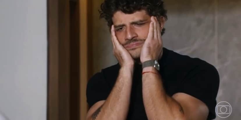 Ari, homem branco com as mãos no rosto e usando camisa preta, em cena da novela Travessia Ari, homem branco com as mãos no rosto e usando camisa preta, em cena da novela Travessia