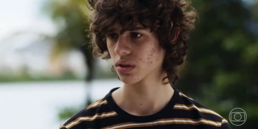 Rudá dentro da novela Travessia usando camisa listrada ao ar livre Rudá dentro da novela Travessia usando camisa listrada ao ar livre