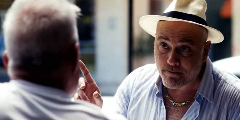 Zezinho em cena da novela Travessia usando chapéu branco e camisa listrada azul Zezinho em cena da novela Travessia usando chapéu branco e camisa listrada azul
