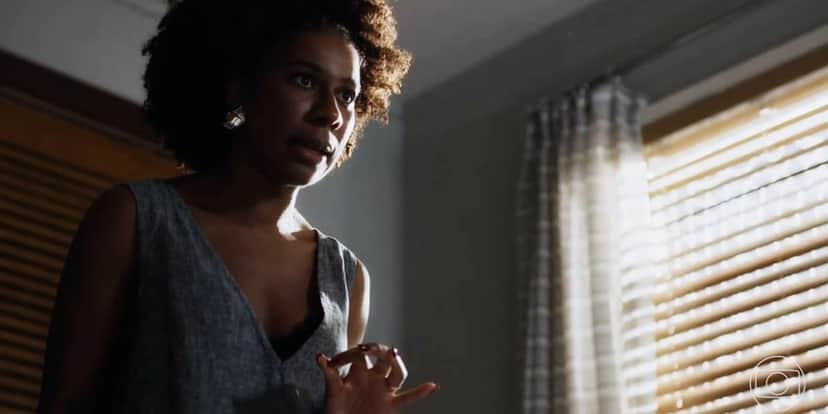 Laís (Indira Nascimento) mulher negra que usa vestido cinza está em cena da novela Travessia. Laís (Indira Nascimento) mulher negra que usa vestido cinza está em cena da novela Travessia.