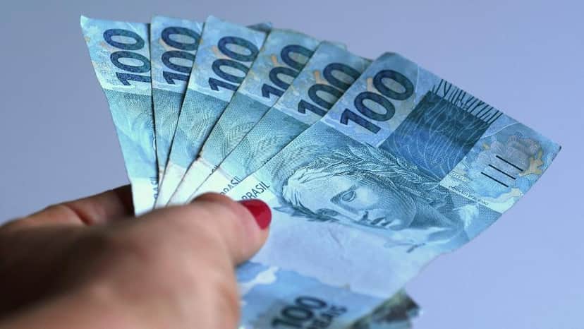Notas de 100 reais seguradas por uma mão (Foto: Reprodução, Uol) Notas de 100 reais seguradas por uma mão (Foto: Reprodução, Uol)