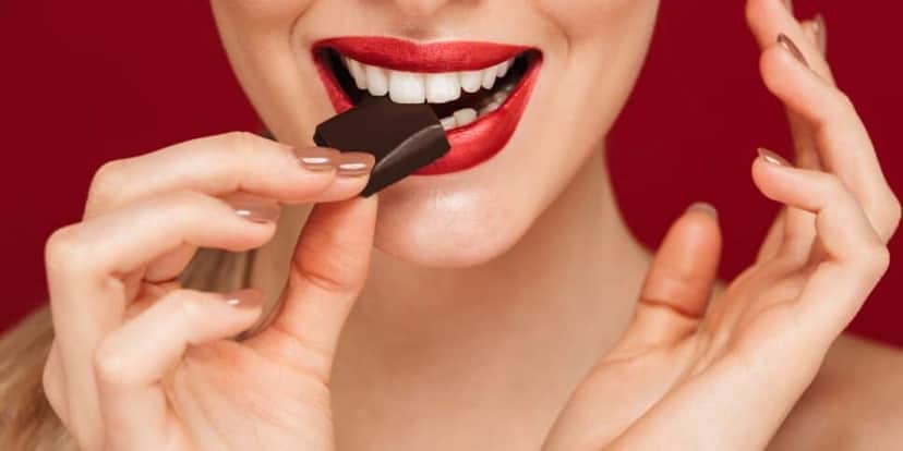 Mulher comendo chocolate (Foto: Canva) Mulher comendo chocolate (Foto: Canva)