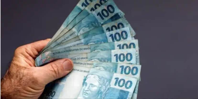 Homem segurando notas de cem reais de abono(Foto: Canva) Homem segurando notas de cem reais de abono(Foto: Canva)