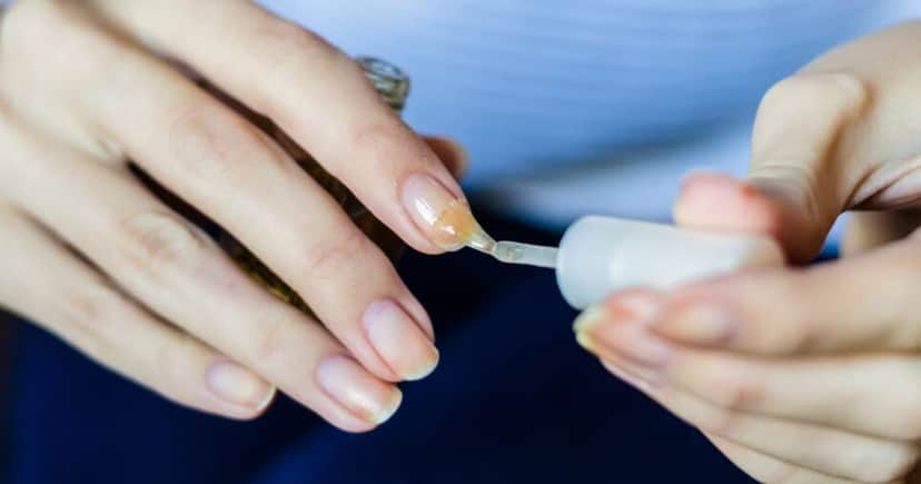 Mulher passando base nas unhas (Foto: Canva) Mulher passando base nas unhas (Foto: Canva)
