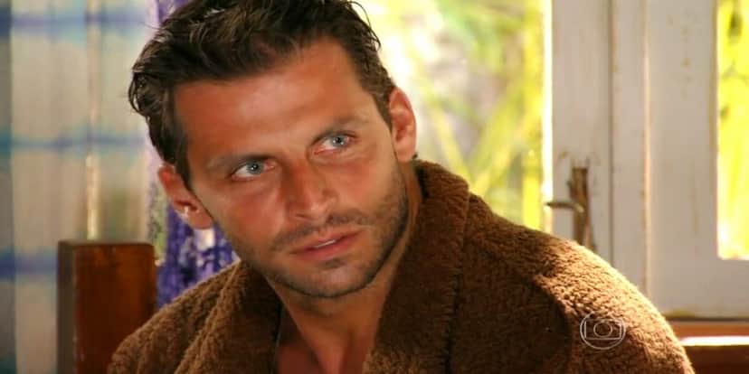 Cassiano em cena da novela Flor do Caribe, ele está sentado e encarando ao seu lado Cassiano em cena da novela Flor do Caribe, ele está sentado e encarando ao seu lado