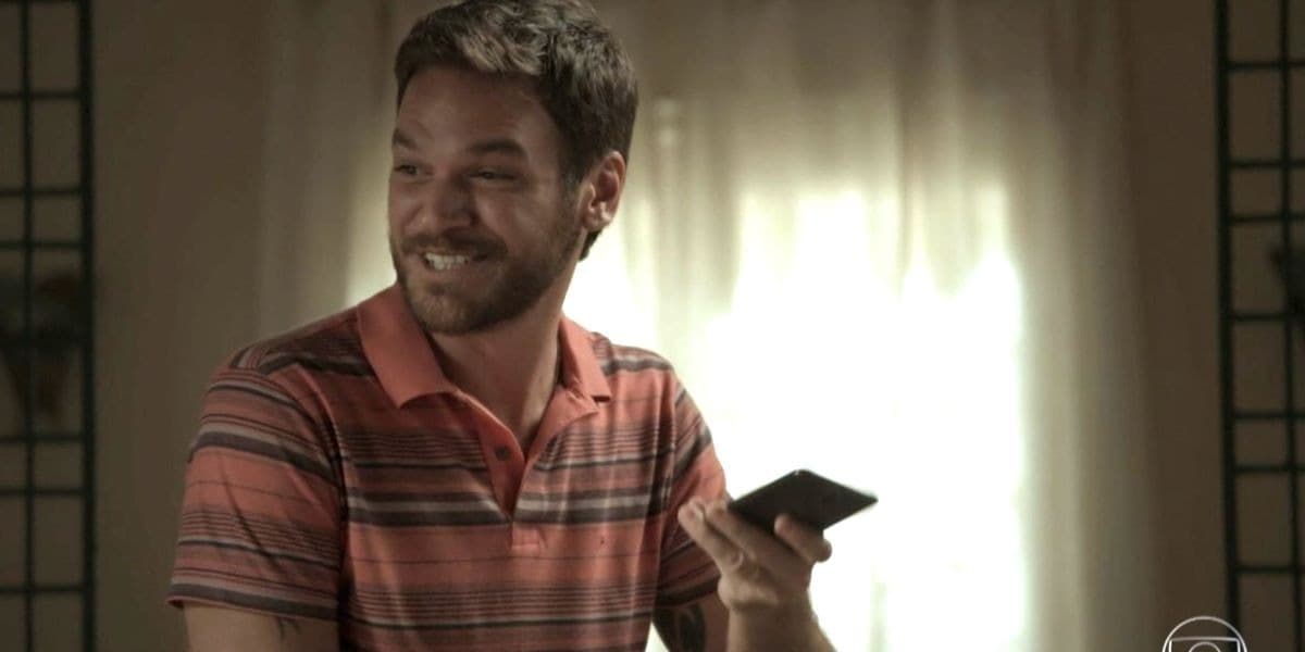 Rubinho em cena de A Força do Querer com telefone na mão e sorrindo Rubinho em cena de A Força do Querer com telefone na mão e sorrindo