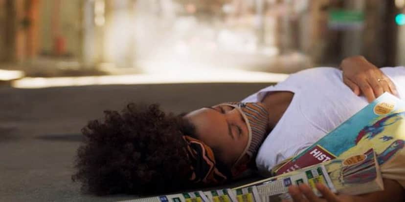 Camila, mulher negra de cabelo black power, caída na rua com livros de história espalhados Camila, mulher negra de cabelo black power, caída na rua com livros de história espalhados