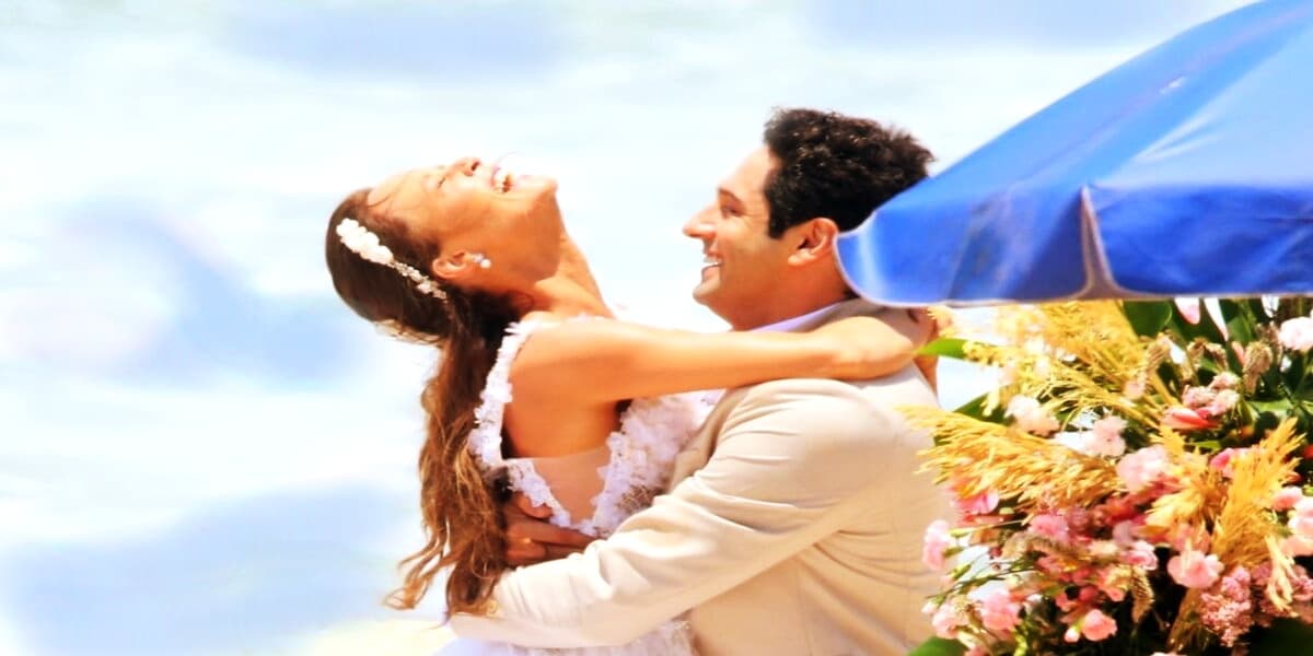 João Baldasserini e Mariana Ximenes vestidos de noivo e noiva em cena de Haja Coração gravada na praia de dia João Baldasserini e Mariana Ximenes vestidos de noivo e noiva em cena de Haja Coração gravada na praia de dia