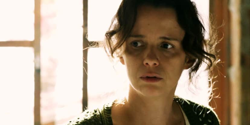 Lorraine usando casaco verde de trico, em contra luz da janela em cena de Império Lorraine usando casaco verde de trico, em contra luz da janela em cena de Império