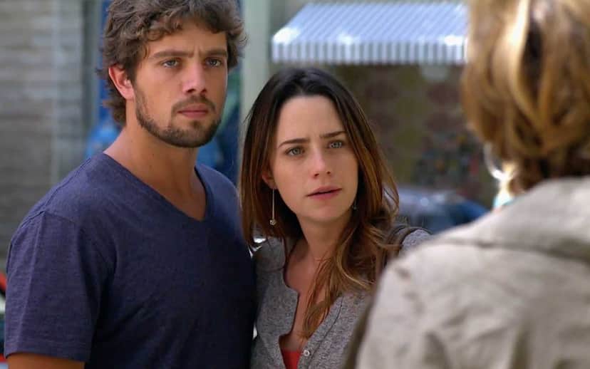 Rodrigo com camisa azul está abraçado a Ana de blusa cinza em cena de dia da novela A Vida da Gente Rodrigo com camisa azul está abraçado a Ana de blusa cinza em cena de dia da novela A Vida da Gente