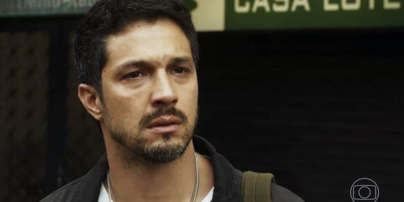 Oto em cena da novela Travessia com olhar triste, usa camisa azul social, camisa branca, seu tom de pele é branco tem barba pequena e cabeço preto curto Oto em cena da novela Travessia com olhar triste, usa camisa azul social, camisa branca, seu tom de pele é branco tem barba pequena e cabeço preto curto