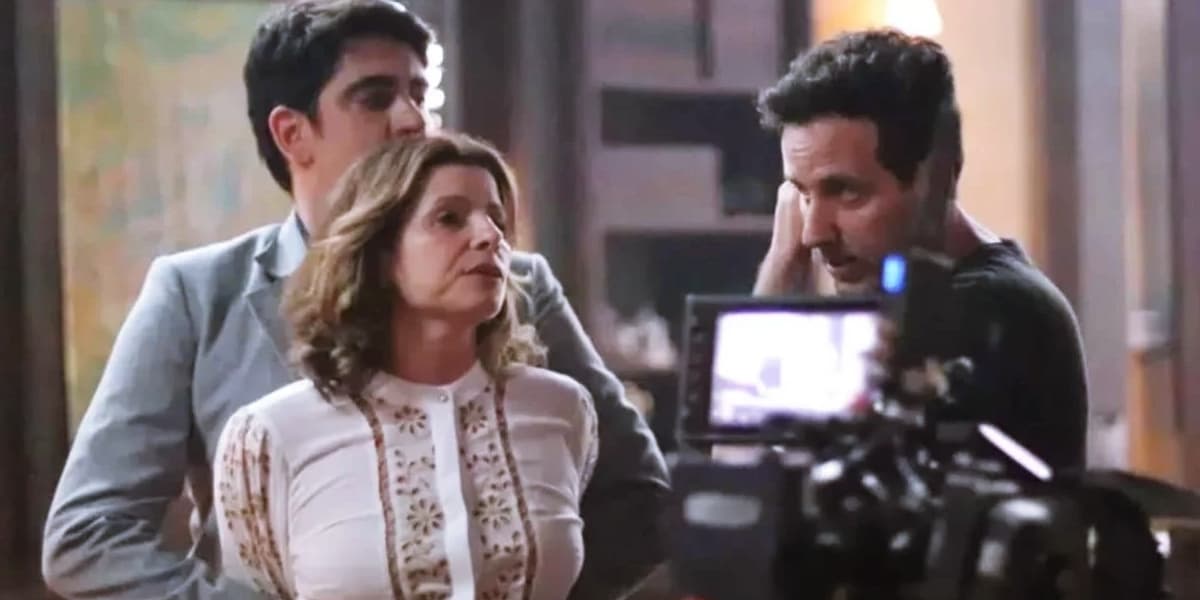 Deodora é segurada por Noé em cena da novela Mar do Sertão e tem uma câmera em primeiro plano Deodora é segurada por Noé em cena da novela Mar do Sertão e tem uma câmera em primeiro plano
