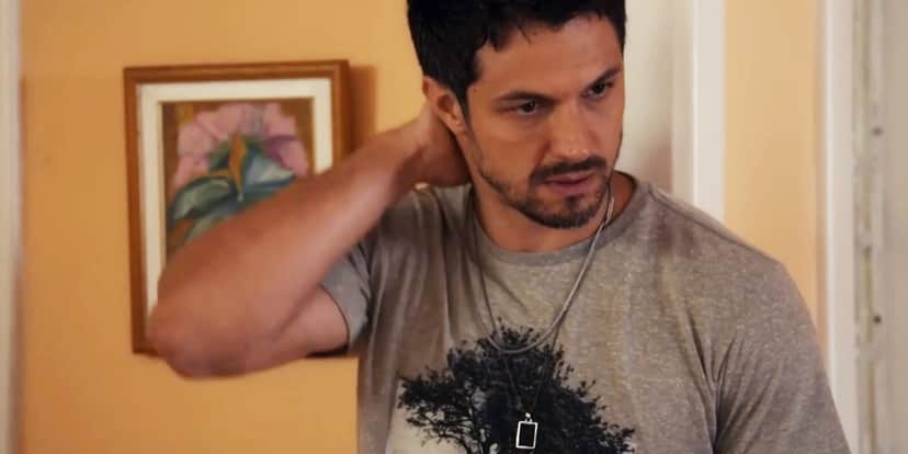 Oto usando camiseta cinza com estampa de uma árvore coloca a mão na nuca em preocupação na novela Travessia Oto usando camiseta cinza com estampa de uma árvore coloca a mão na nuca em preocupação na novela Travessia