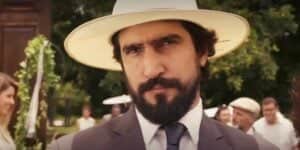 Tertulinho na novela Mar do Sertão usando chapéu branco, terno cinza, gravata azul e camisa branca com expressão brava Tertulinho na novela Mar do Sertão usando chapéu branco, terno cinza, gravata azul e camisa branca com expressão brava