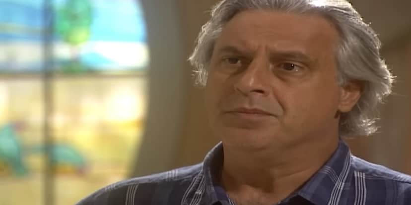 Bruno em cena da novela O Rei do Gado usando cabelo grisalho e camisa azul xadrez Bruno em cena da novela O Rei do Gado usando cabelo grisalho e camisa azul xadrez