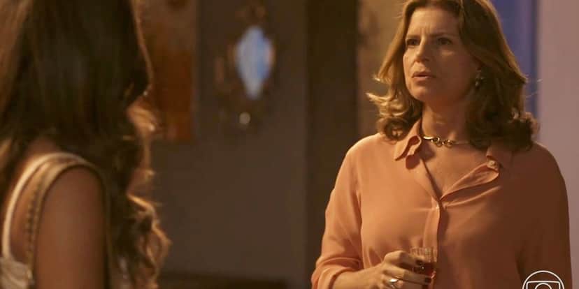 Deodora usando camisa rosa e segurando uma pequena taça encara Candoca em Mar do Sertão Deodora usando camisa rosa e segurando uma pequena taça encara Candoca em Mar do Sertão