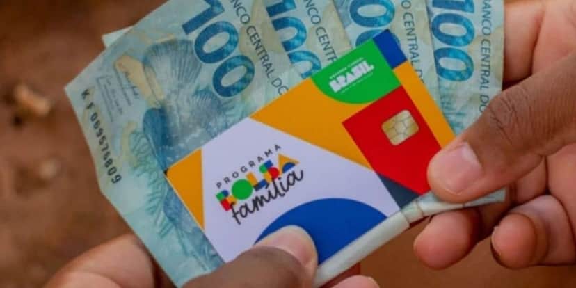 Pessoa segurando notas de cem reais e cartão do Bolsa Família (Foto: Reprodução / Internet) Pessoa segurando notas de cem reais e cartão do Bolsa Família (Foto: Reprodução / Internet)