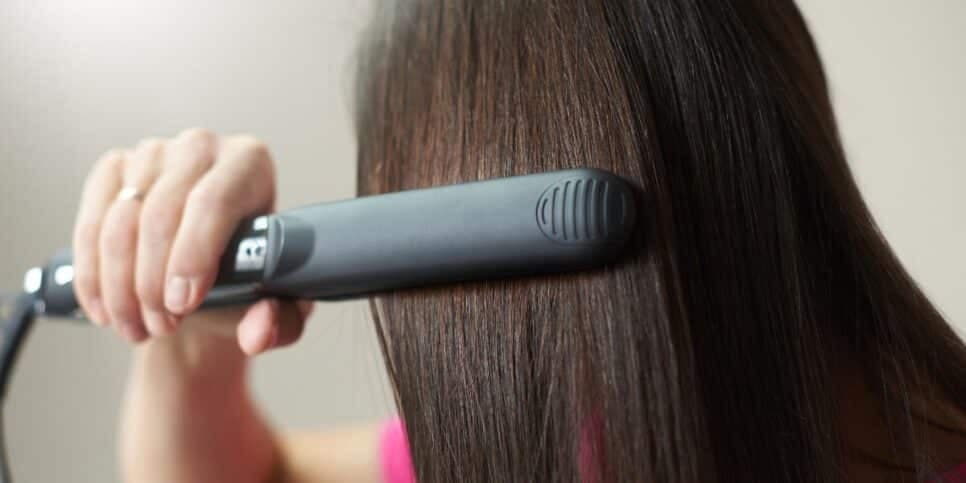 Mulher alisando o cabelo com chapinha (Foto: Reprodução / Canva) Mulher alisando o cabelo com chapinha (Foto: Reprodução / Canva)